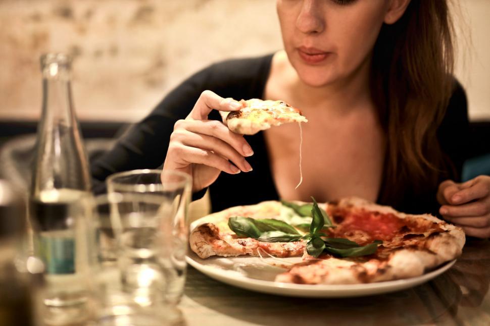 woman-holding-sliced-pizza-to-eat